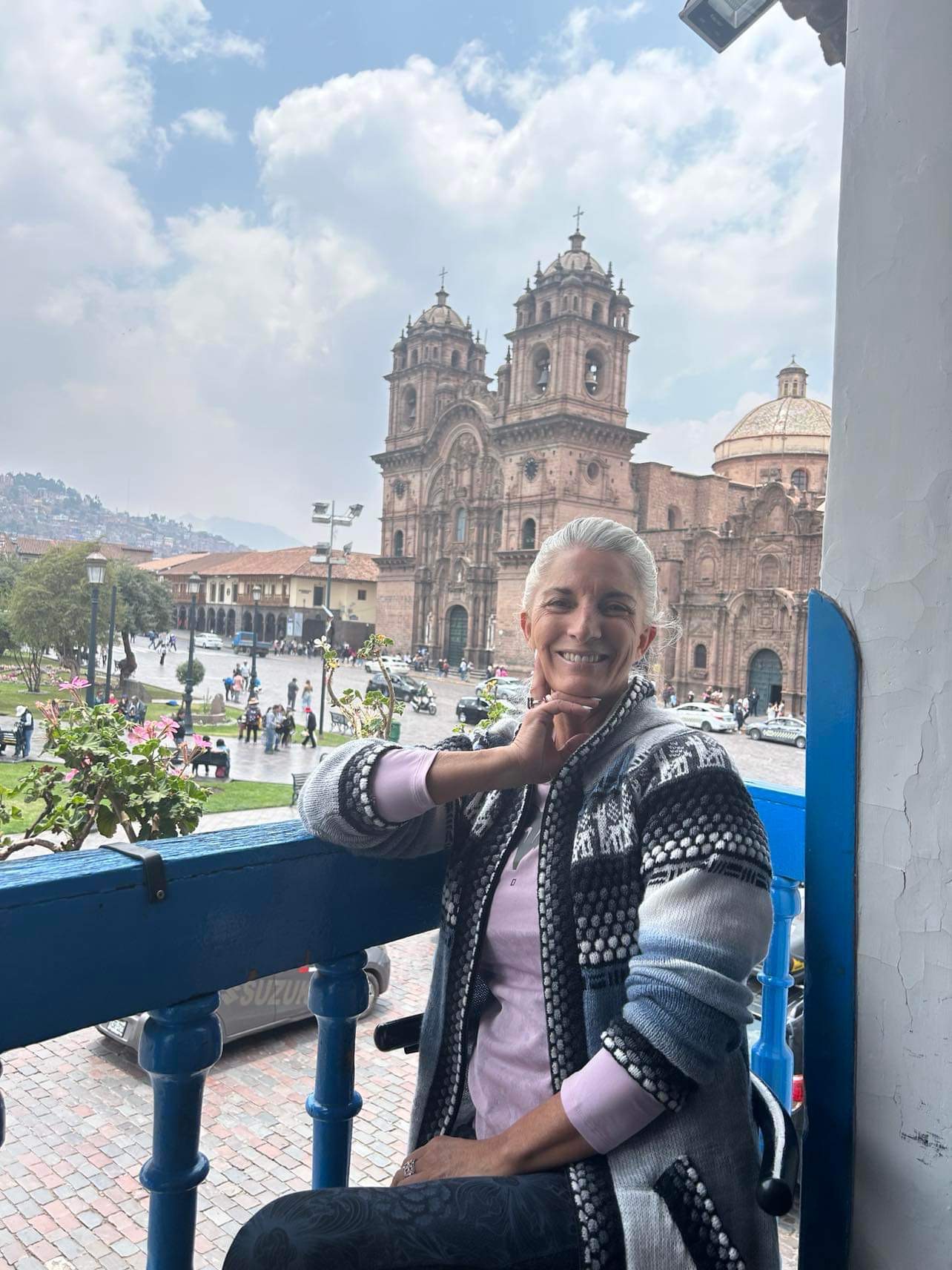 Armanda seated on a balcony overlooking a square and an ornate stone building