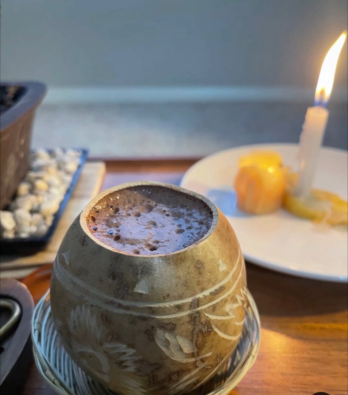A ceramic cup beside a lit candle