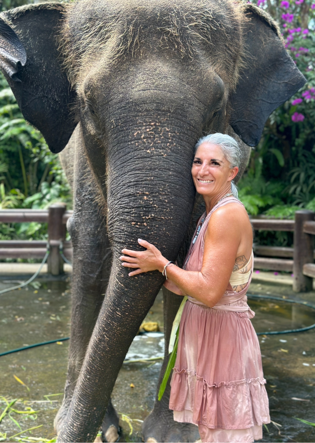 Armanda smiling beside an elephant in a leafy setting