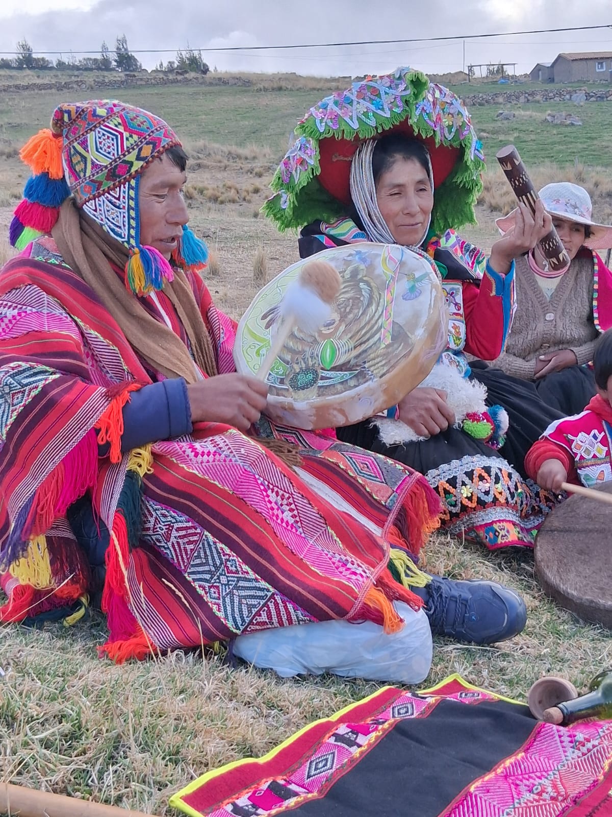 People gathered outdoors with a drum and colourful woven clothing