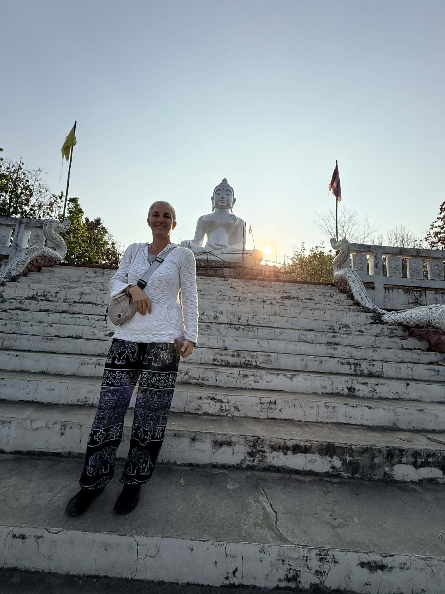 Armanda standing with palms together on wide stone steps at sunset