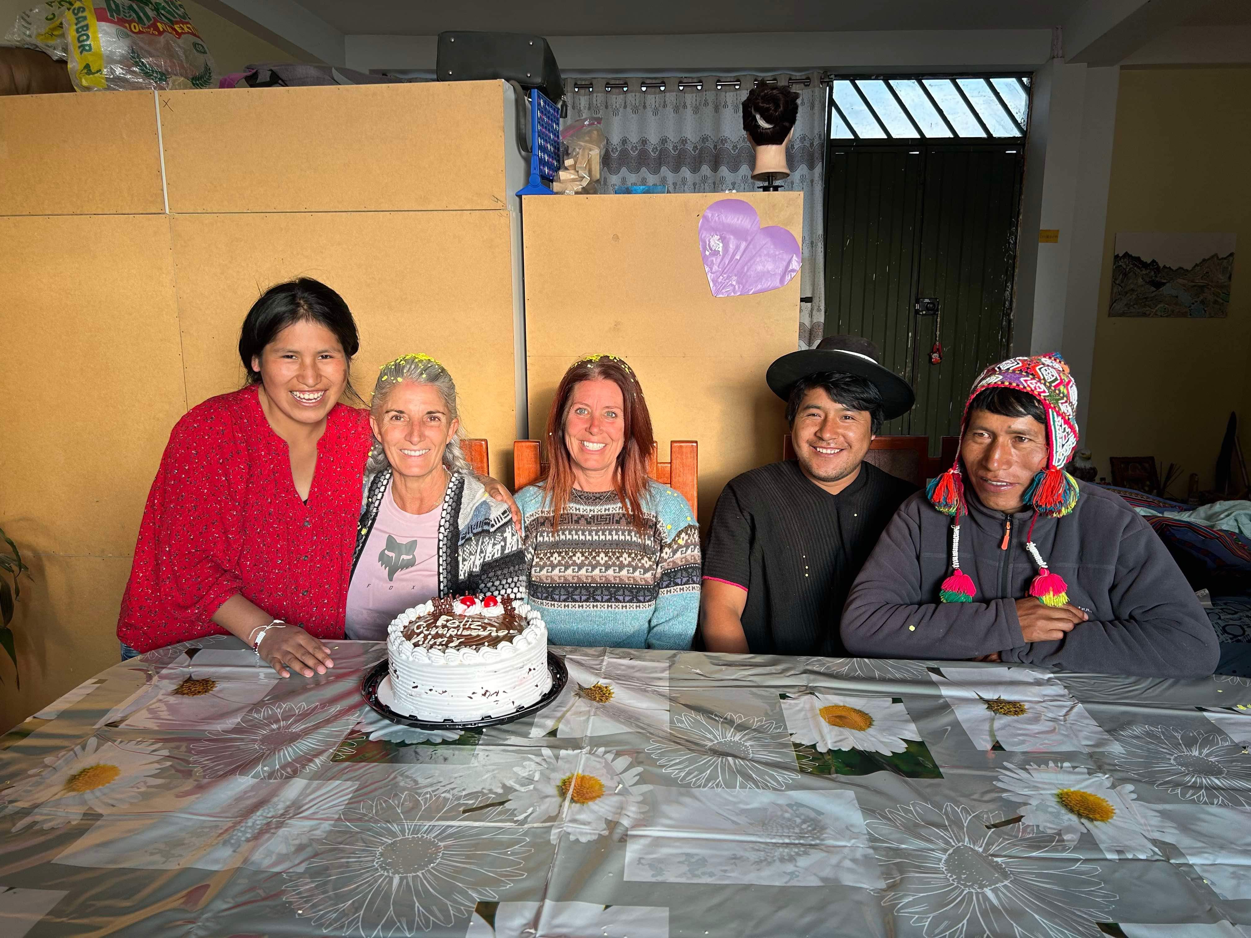 Five people seated around a table with a decorated cake