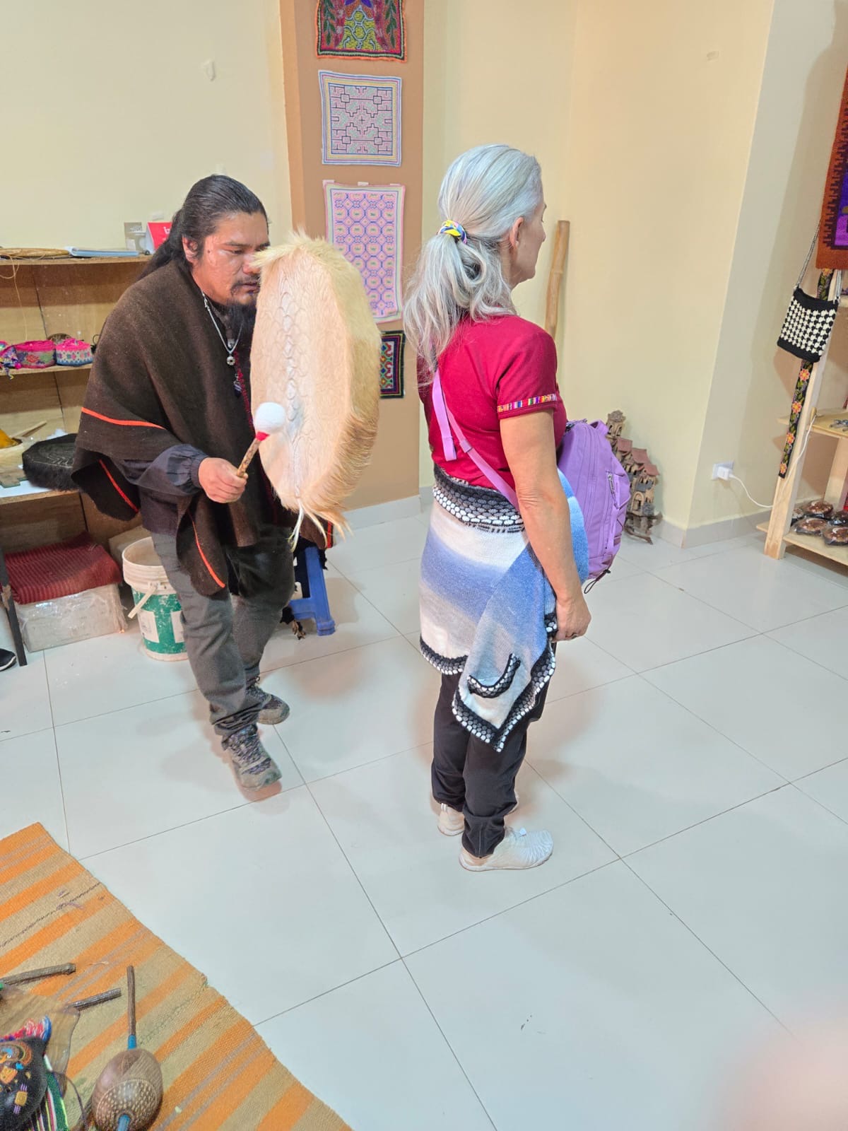 A person holding a large drum near Armanda during an indoor gathering