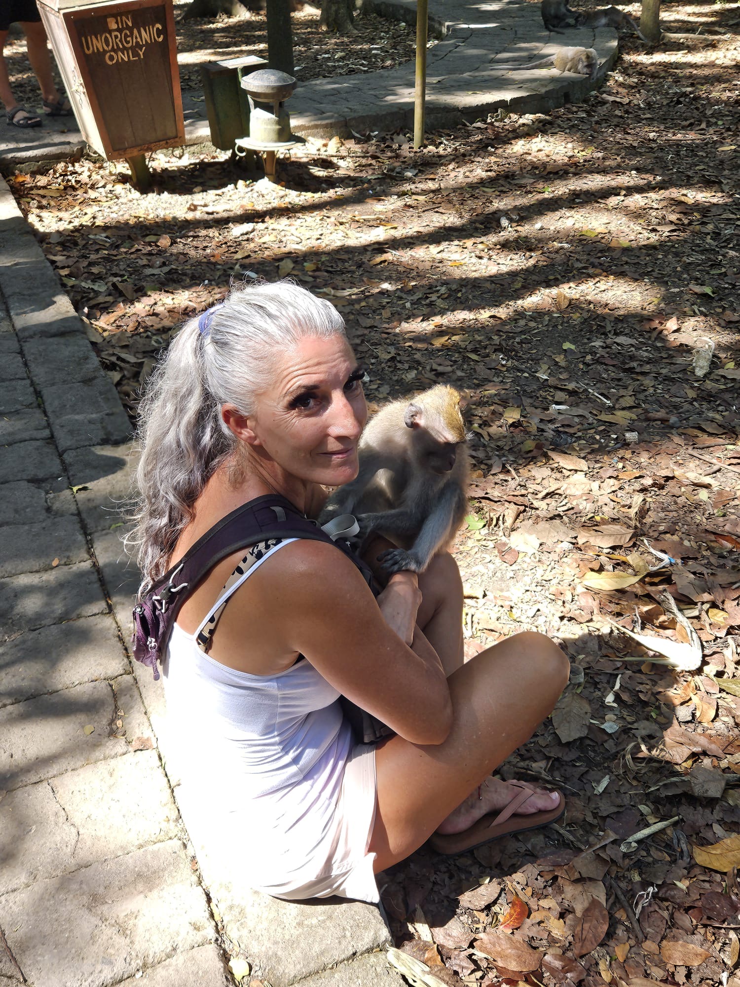Armanda crouching beside a small animal in a wooded setting